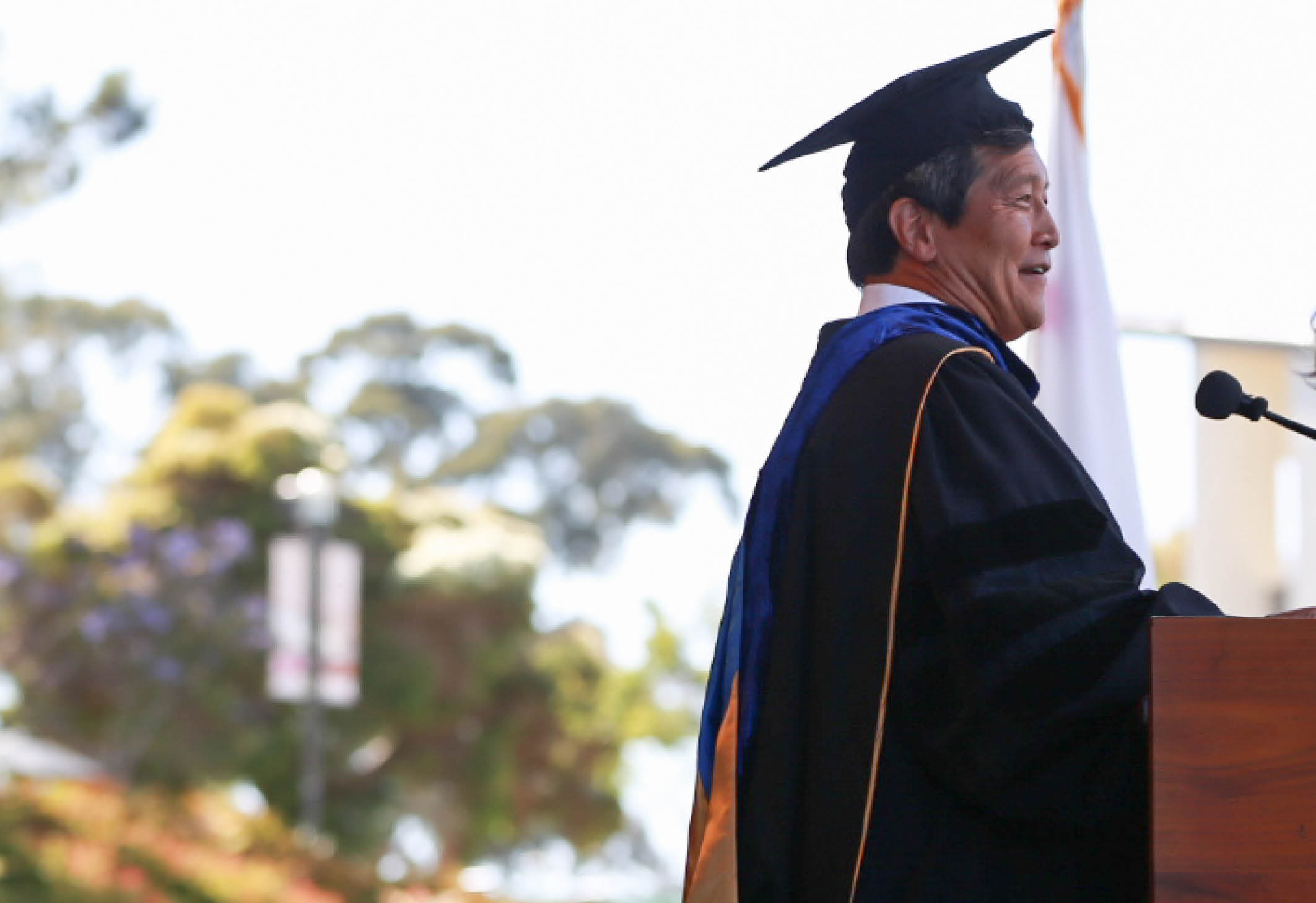 Yulun Wang in cap and gown delivering the keynote address at the 2024 UCSB COE Undergraduate Commencement