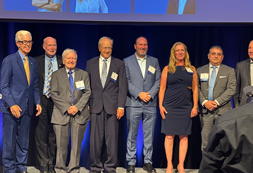 John Bowers stands on stage with former California Gov. Gray Davis and other University of California innovation award recipients following the ceremony.