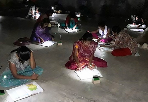 Female students in India study with solar-powered LED lights from Unite to Light.