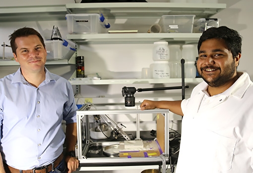 Associate professor Alban Sauret (left) and first-year PhD student Ram Sharma with the experimental setup to test crater resulting from the dynamics of result  cohesion, turbulence, erosion, and transport