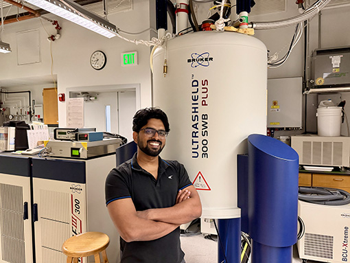 Image of researcher Asish Ninan Chacko standing in front of MRI in the Materials Research Laboratory at UC Santa Barbara