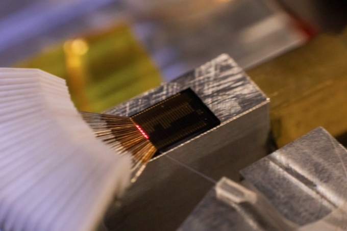 Laser light glows on the surface of a photonics chip. Photograph by Matt Perko