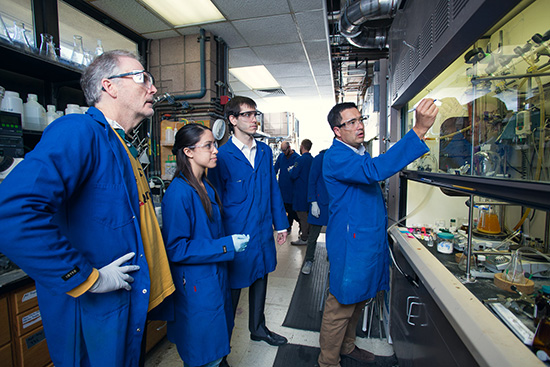 Faculty and students discuss a formula in the Dow lab.